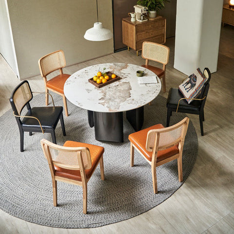 Round marble-top dining table with dark gray pedestal base paired with cassie black dining chair in wood and leather