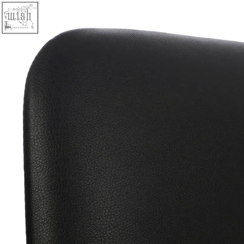 Back side of cassy black leather dining chair with subtle pebbled texture and white legs visible