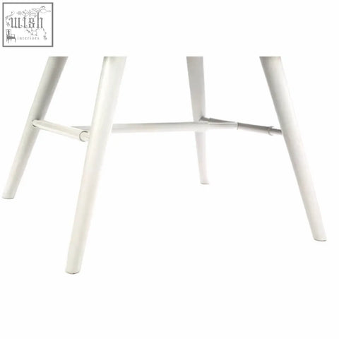 White legs of cassy black leather dining chair with minimalist metal stool legs and angled supports visible from the back