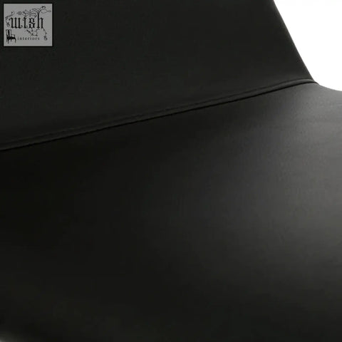Close-up of cassy black leather dining chair seat with smooth surface and white legs visible at the edge