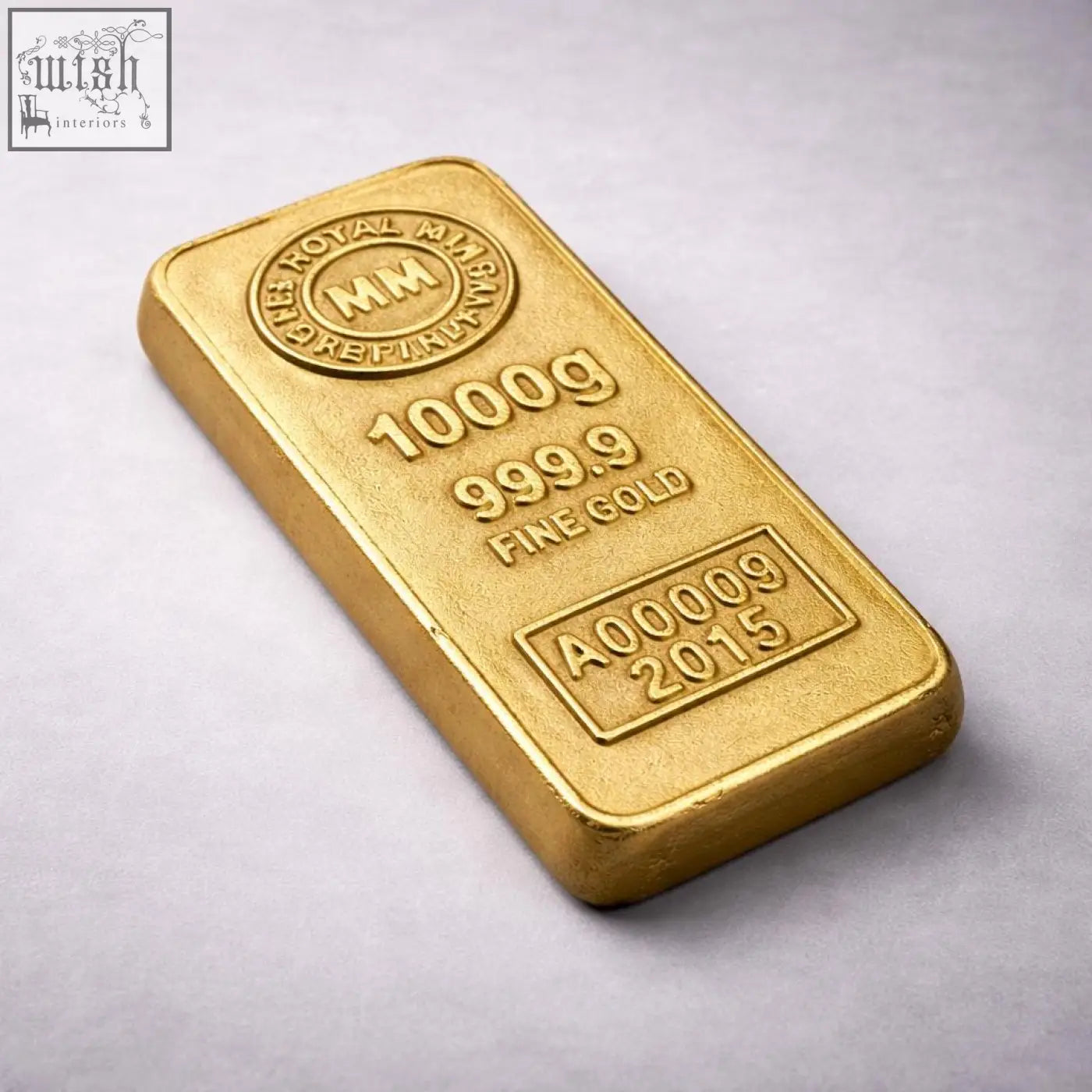 A solid cast aluminium 1000g royal mint gold bar with polished surface and engravings used as a paperweight