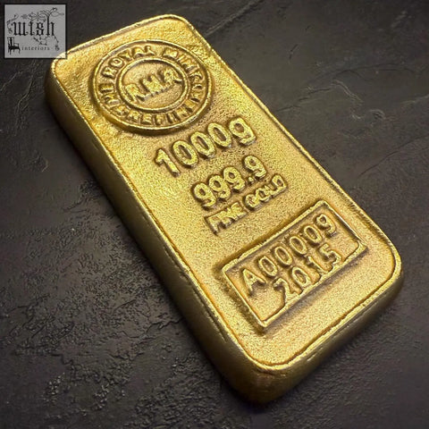 A polished gold cast aluminium bullion bar paper weight with engraved purity and weight markings