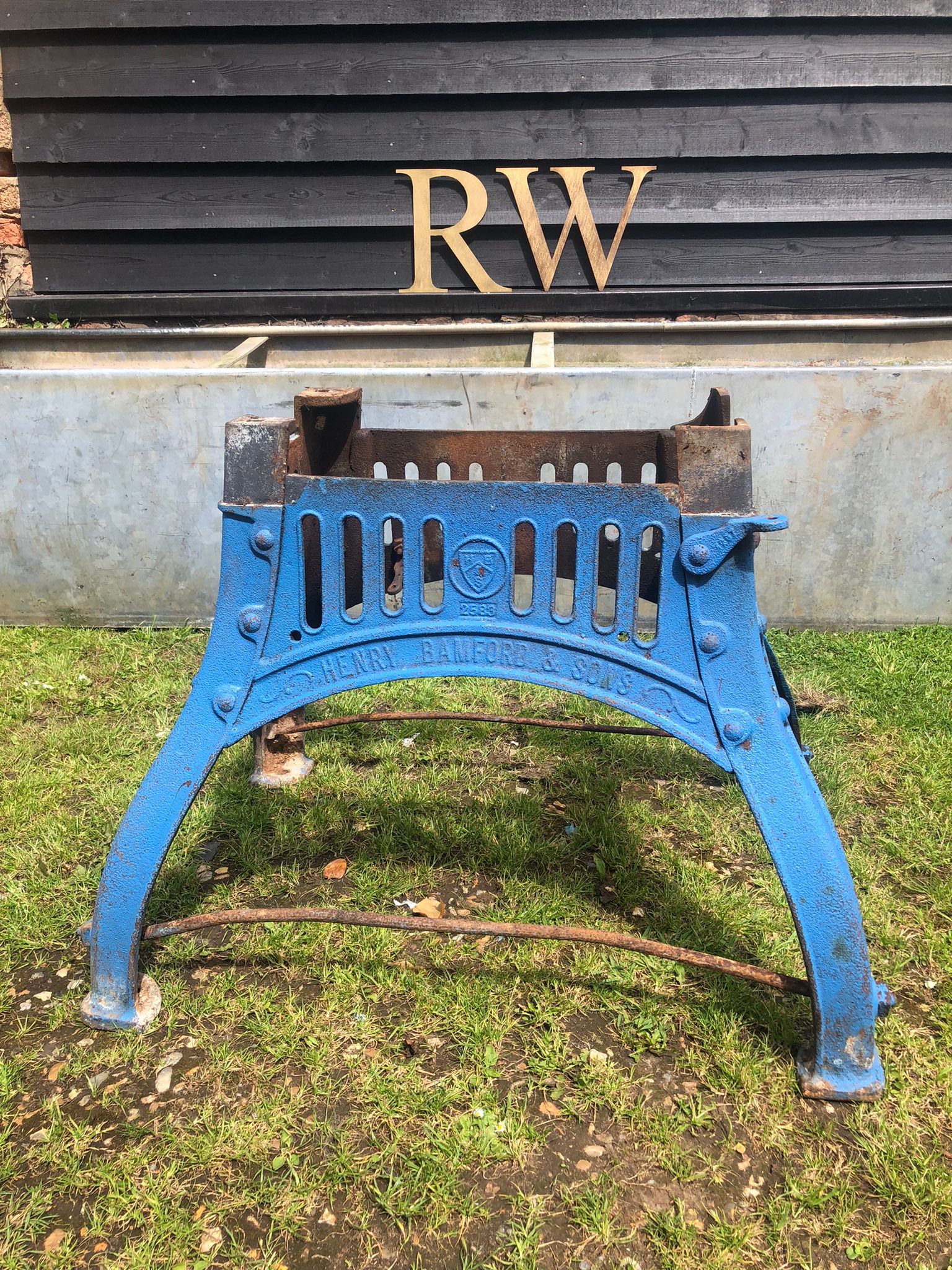 Blue cast iron fire grate with rusted bars and engraved branding for reclaimed original henry bamford table base
