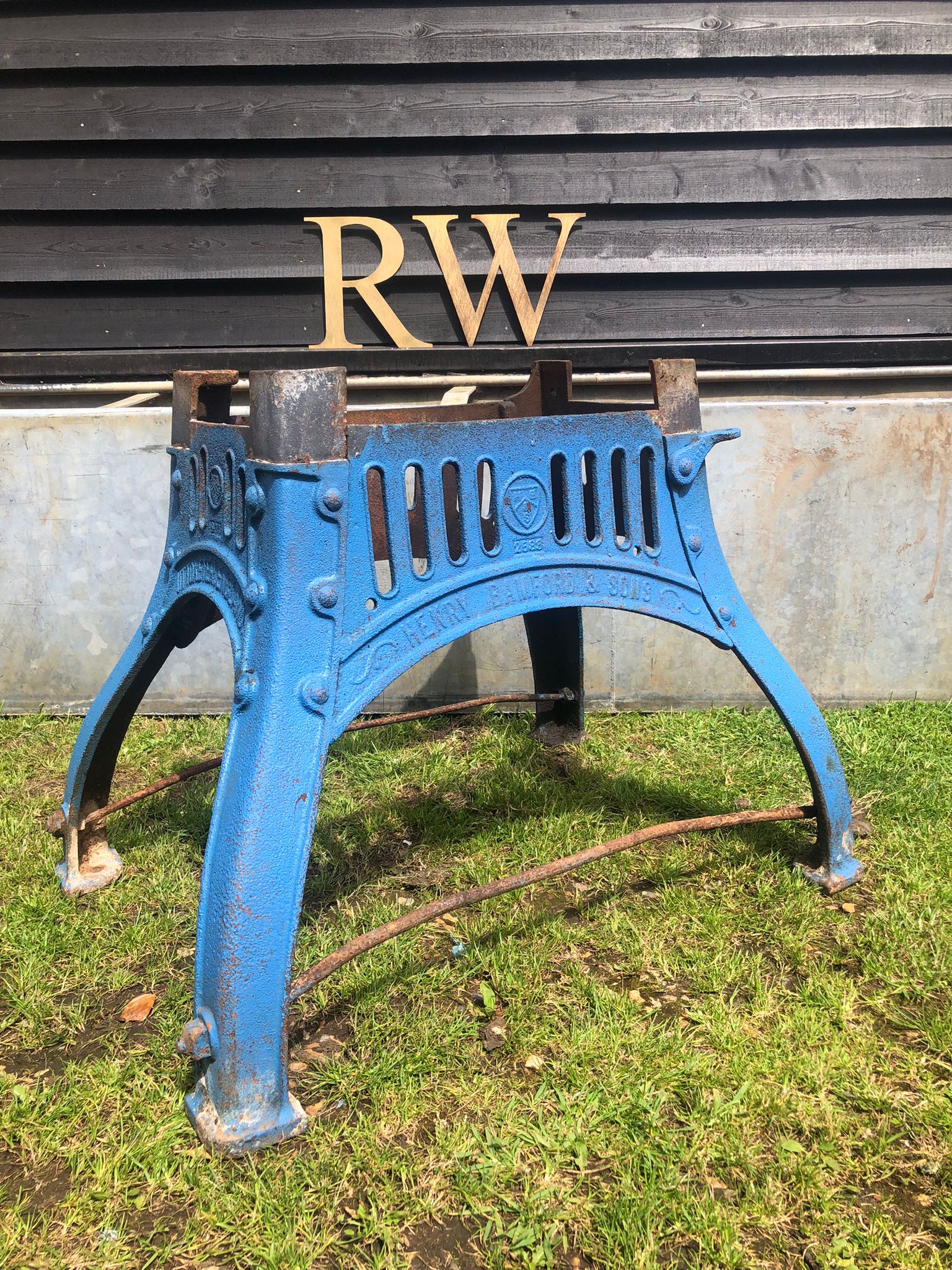 Blue cast iron industrial stool with arched legs and decorative slatted front panel for reclaimed original table base