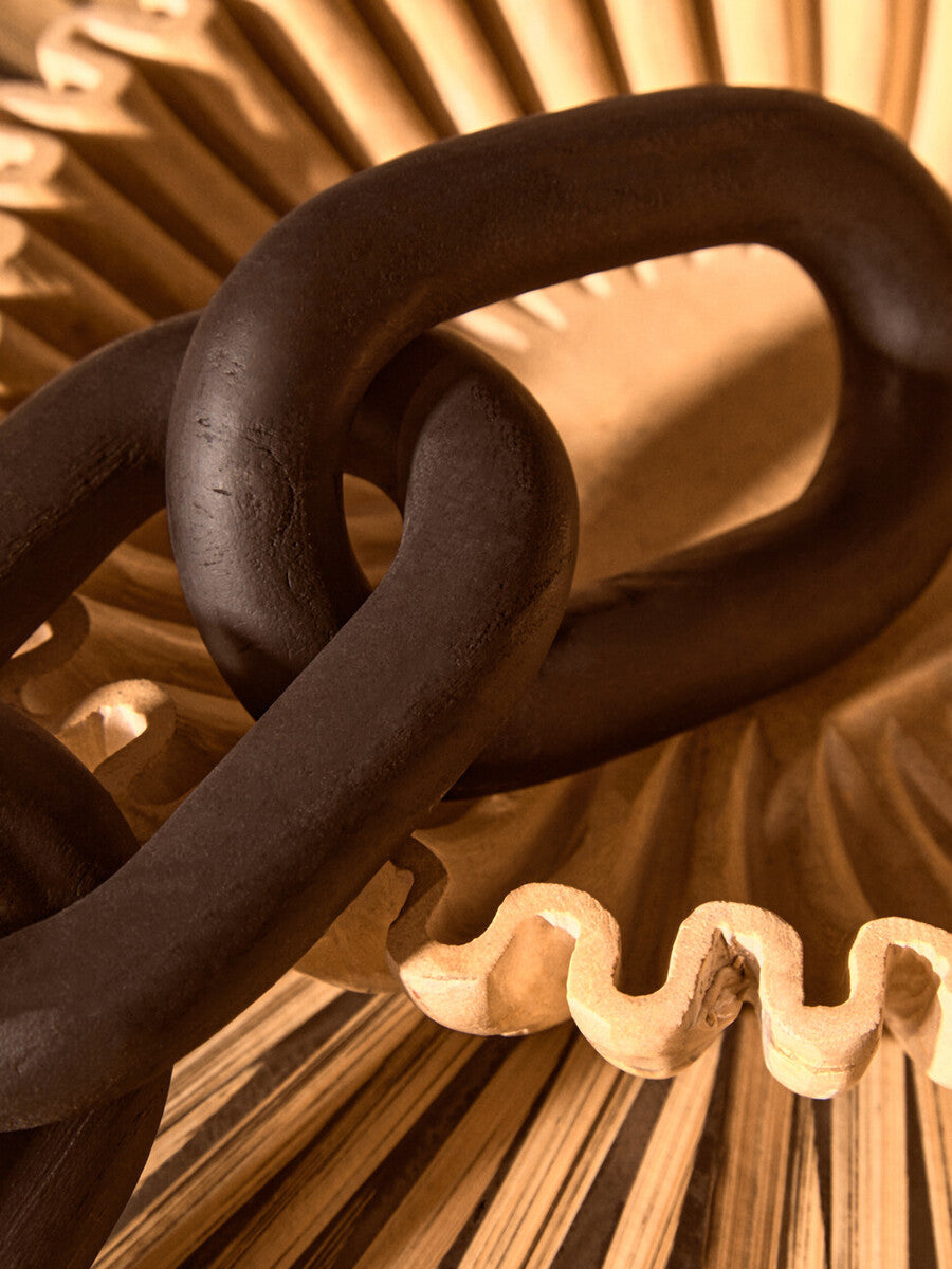 Dark matte black wood link chain decor with interlocking links resting on a light wooden fan structure