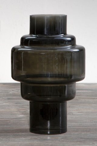 A sleek small black smoked glass vase with tiered smooth cylindrical segments and a dark smoky hue