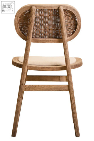 A rustic grey wash elm wood dining chair with a woven cane backrest and beige cushioned seat