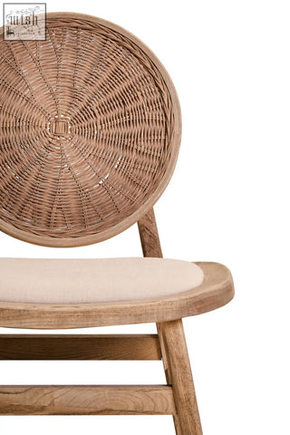 A natural-toned dining chair with a circular rattan backrest and cream cushion on white wash elm wood frame