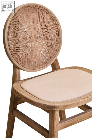 A natural-toned white wash elm wood dining chair with a circular woven rattan back and beige fabric seat