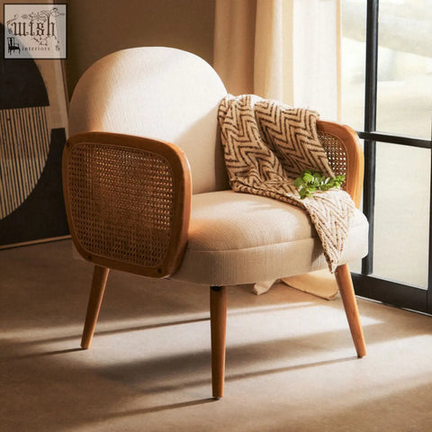 A cozy cebu ivory fabric and cane chair with comfortable seating, elm wood legs, and a patterned throw blanket