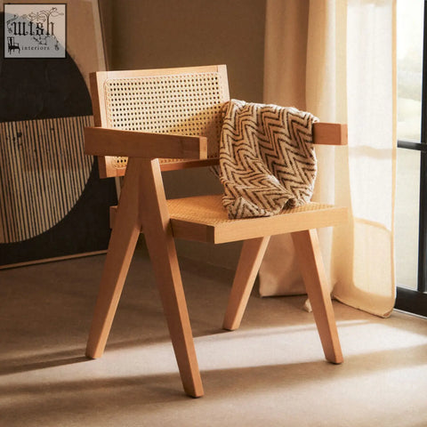 A light wood cebu natural cane and beech wood dining chair with woven back and seat and a cozy throw on armrest