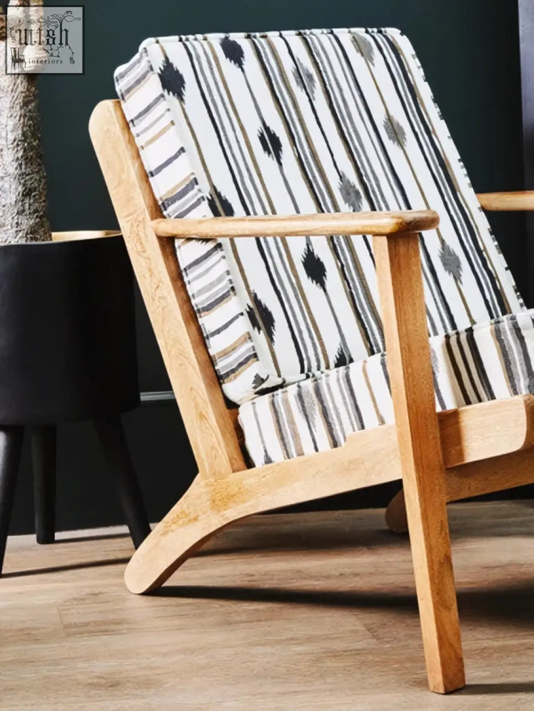 Cefena armchair with angular arms features a light wood frame and a patterned surface cushion in black white and gray stripes
