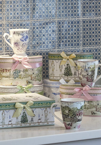 A white ceramic mug from celeste blooming garden mugs set with delicate floral pattern and pastel ribbons on lid