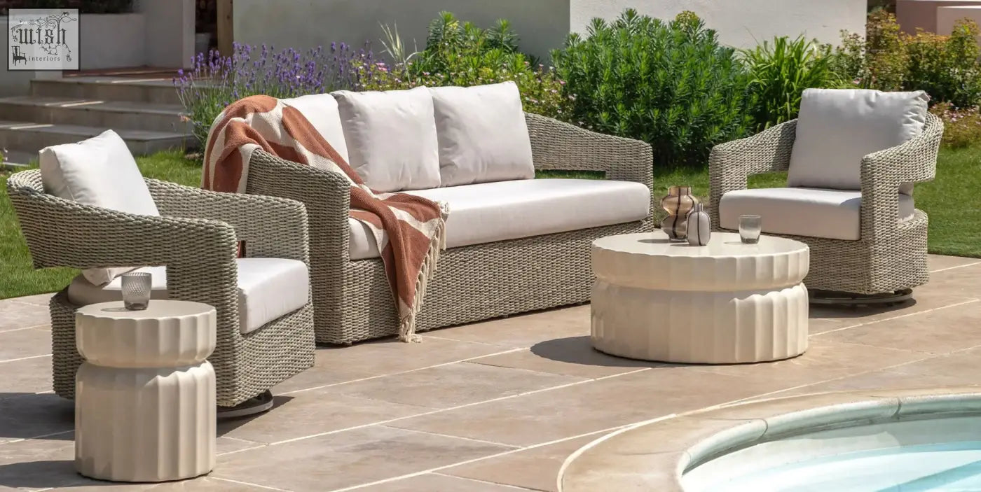 Beige wicker outdoor sofa set with white cushions and a terracotta throw near celino coffee table with cream glazed surface