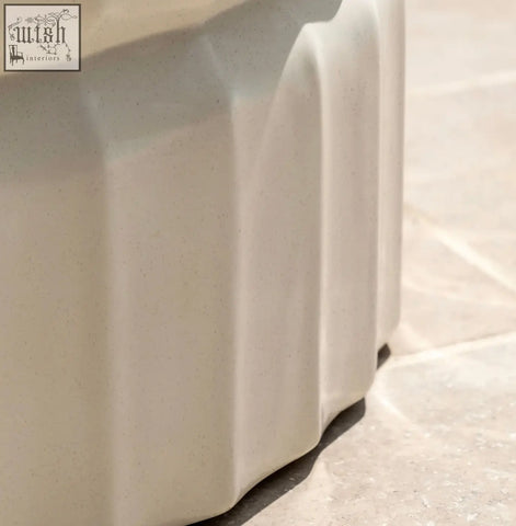 Cream-colored ceramic planter with vertical fluted ridges and a cream glazed surface on celino coffee table features