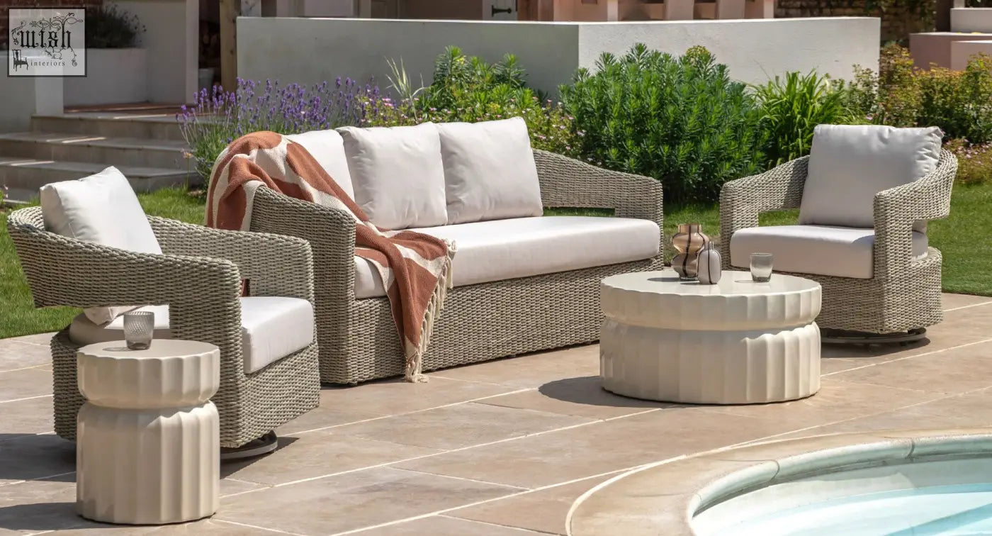 Beige wicker outdoor sofa set with white cushions and striped throw blanket next to celino side table with modern ridge pattern