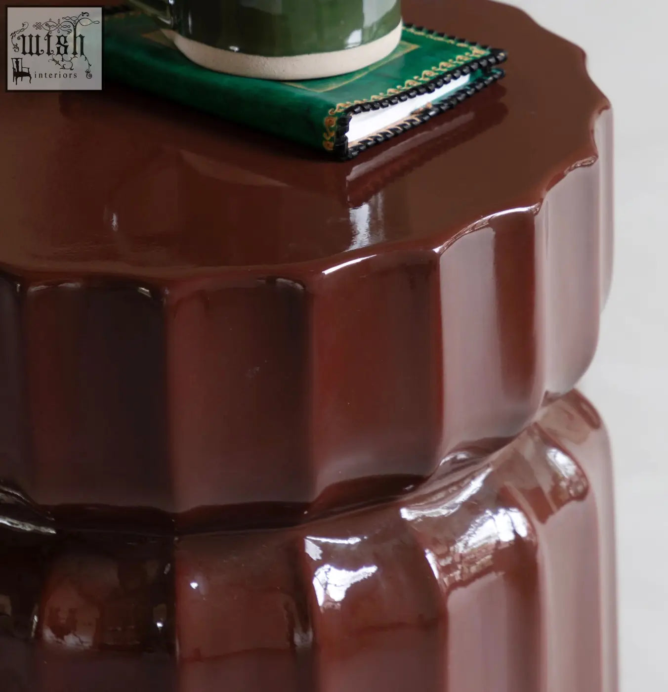 Celino side table is a glossy dark brown ceramic piece with a modern ridge pattern and fluted petal-like design