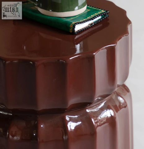 Celino side table is a glossy dark brown ceramic piece with a modern ridge pattern and fluted petal-like design