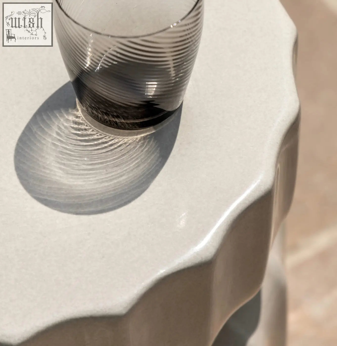 Celino side table with a translucent gray glass tumbler featuring a modern ridge pattern and subtle concentric ridges