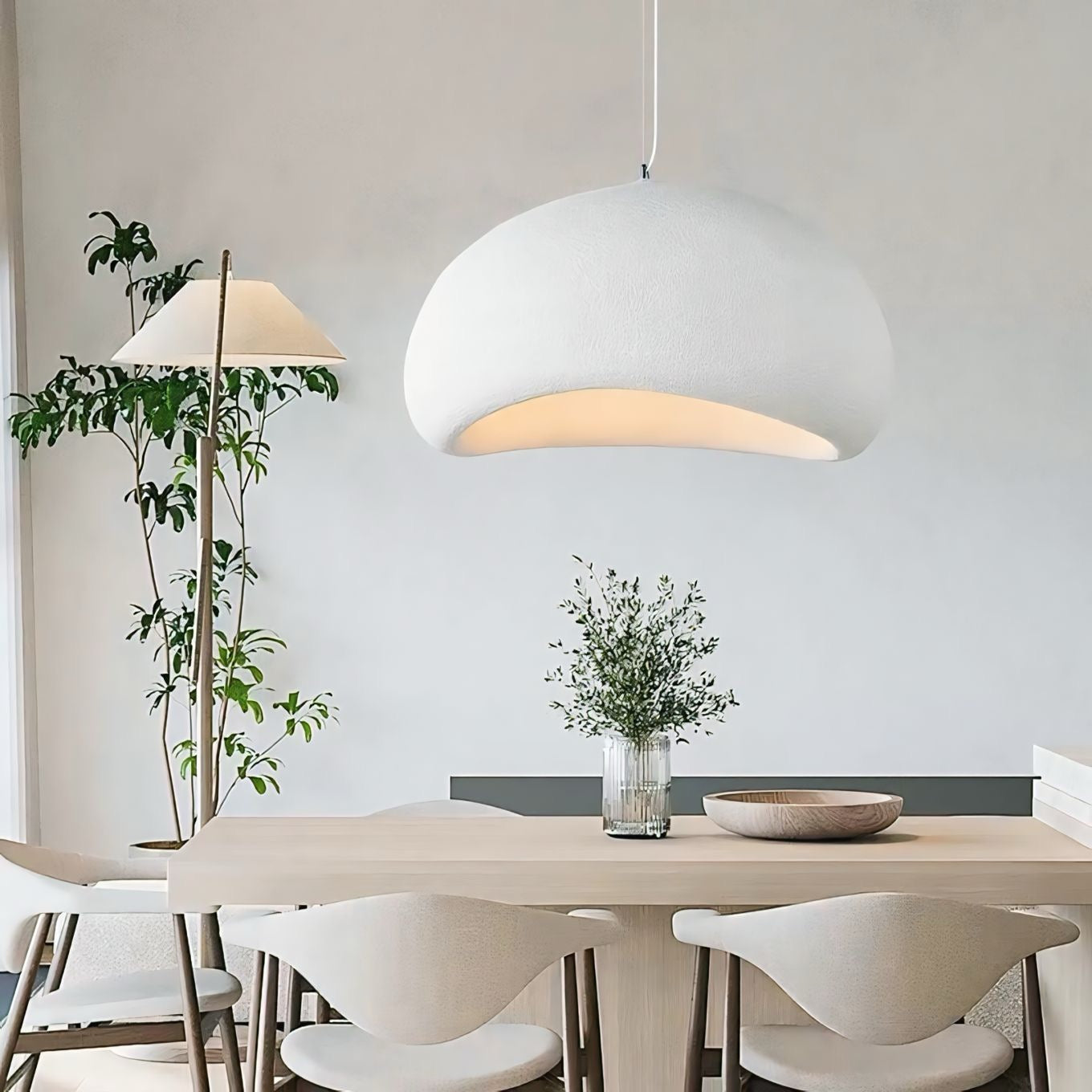 A sleek white dome-shaped chandan light pendant with soft glow and minimalist design hanging above dining table