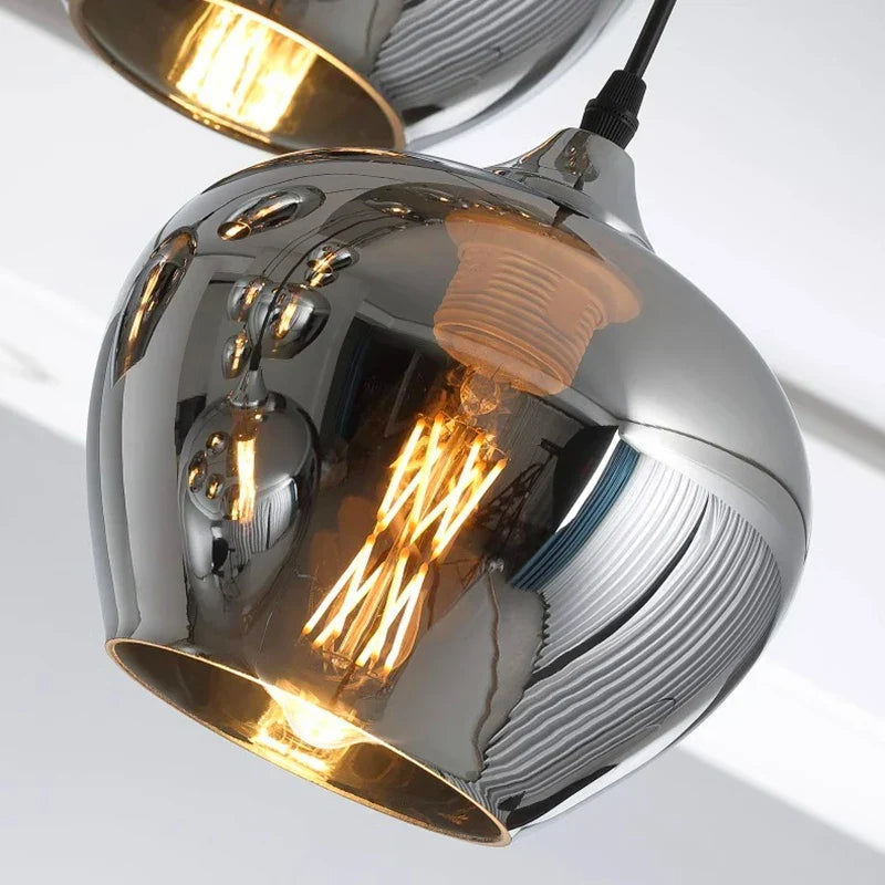 Chrome finished pendant light with reflective rounded globe and exposed bulb for dining room with warm white light