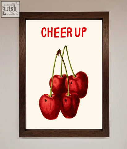A vibrant cherries framed wall art with red cherries and green stems topped by cheer up text on an off-white background