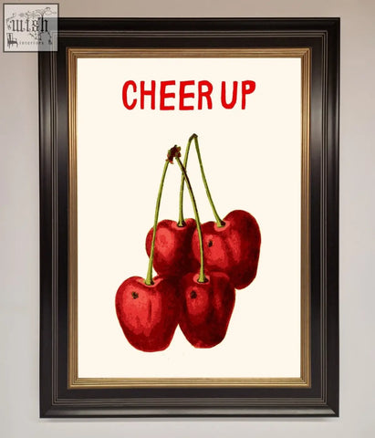 A framed wall art featuring vibrant red cherries with green stems and bold cheer up text on a cream background