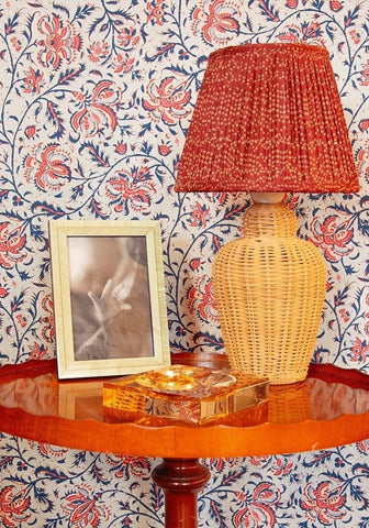 A chelsea amber glass trinket tray in brown shown with a woven yellow lamp and pleated red fabric shade