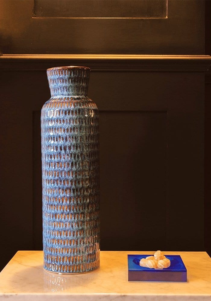 Tall blue ceramic vase with textured ribbed surface and brownish glaze accents beside chelsea cobalt glass trinket tray