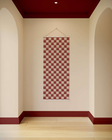 A red and beige chequerboard wall tapestry with white border hanging by a thin string for room decor