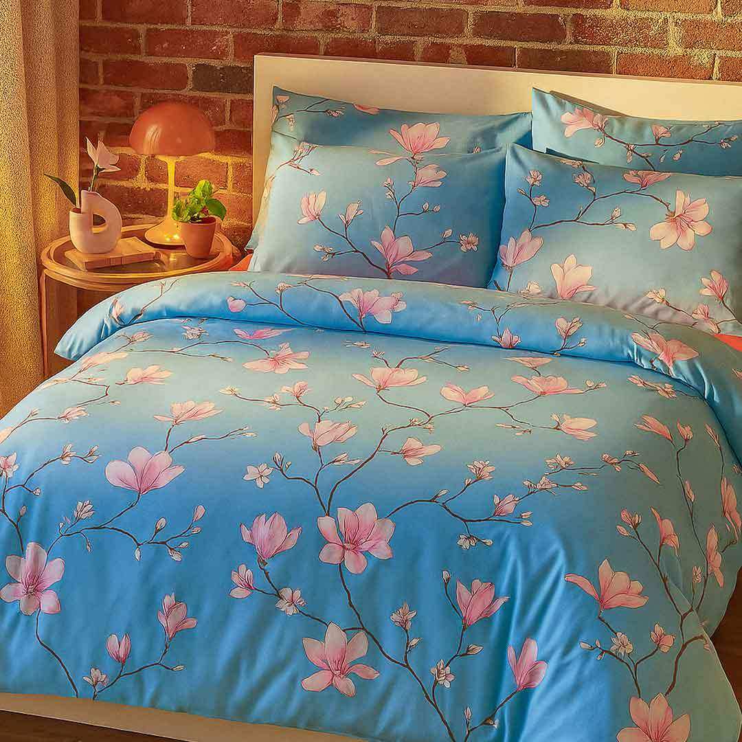 Blue satin duvet cover with pink magnolia blossoms and branches from cherry blossom bedding set flat bed sheet look