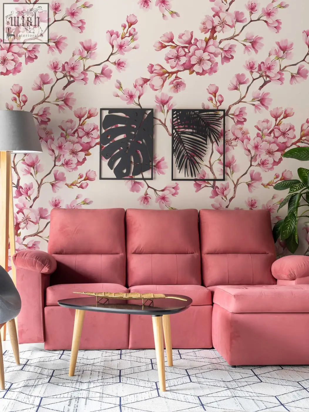 Pink upholstered sectional sofa with tufted cushions and wooden legs in living space with cherry blossom mural removable wallpaper