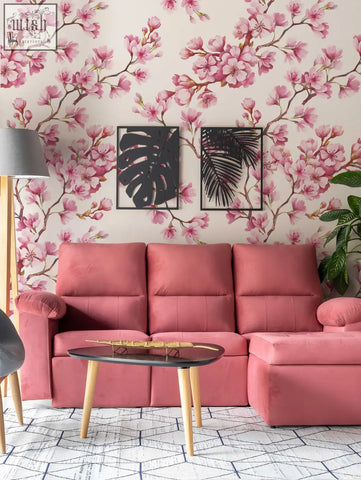 Pink upholstered sectional sofa with tufted cushions and wooden legs in living space with cherry blossom mural removable wallpaper