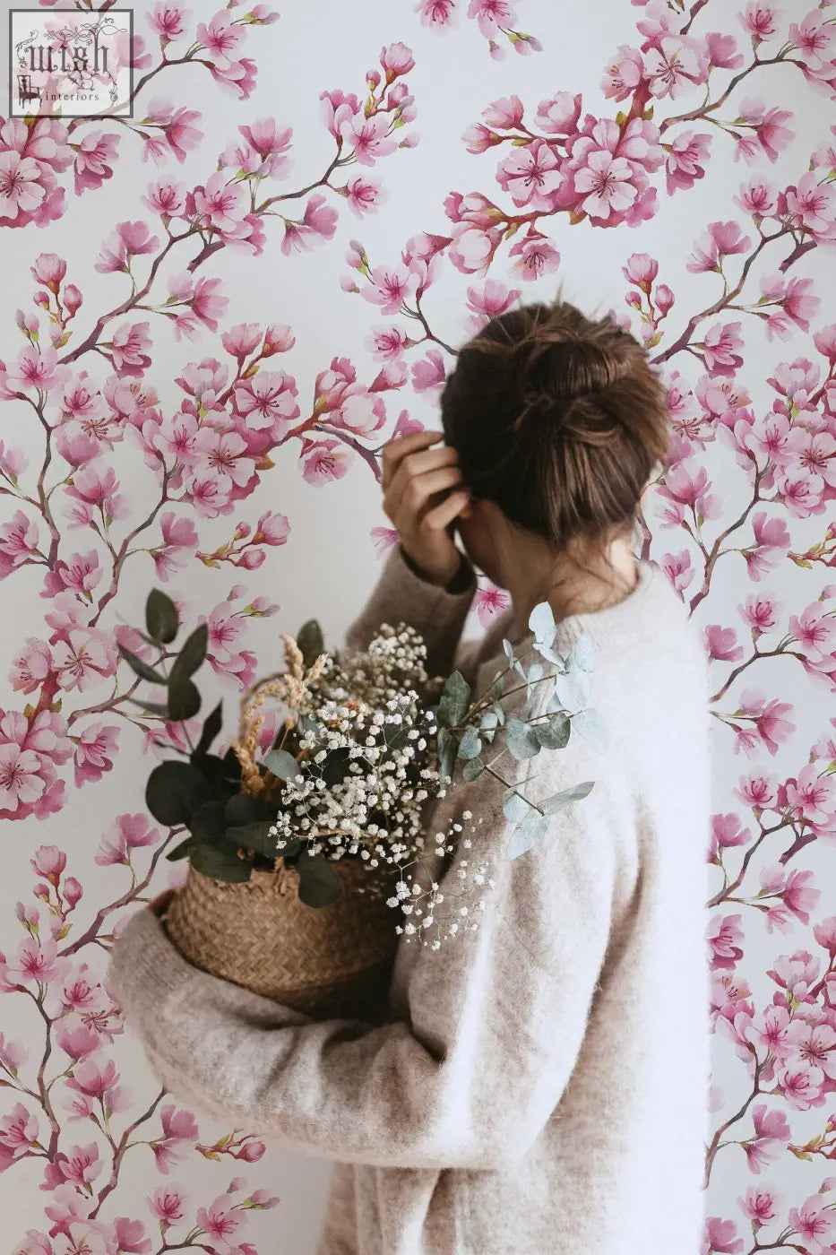 A woven wicker basket with white babys breath and green eucalyptus complements cherry blossom mural removable wallpaper for living space