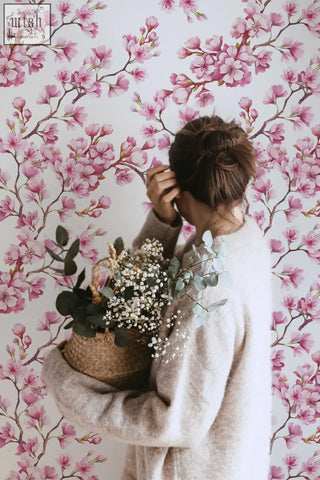 A woven wicker basket with white babys breath and green eucalyptus complements cherry blossom mural removable wallpaper for living space