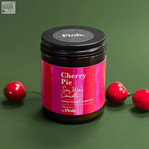 A dark amber glass jar with a vibrant pink and magenta striped label holds a cherry pie apothecary candle by floh