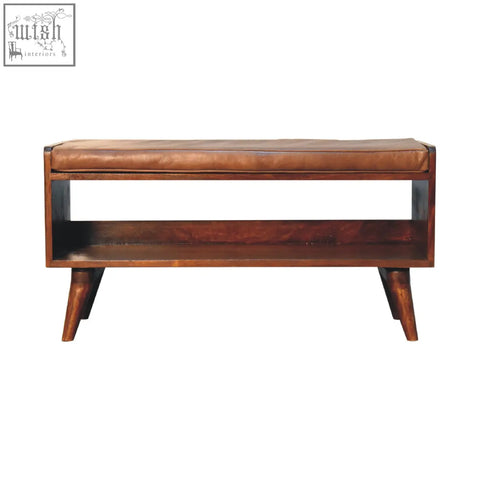 Chestnut bench with brown leather seatpad features a brown leather seat and wooden tapered legs with a lower shelf