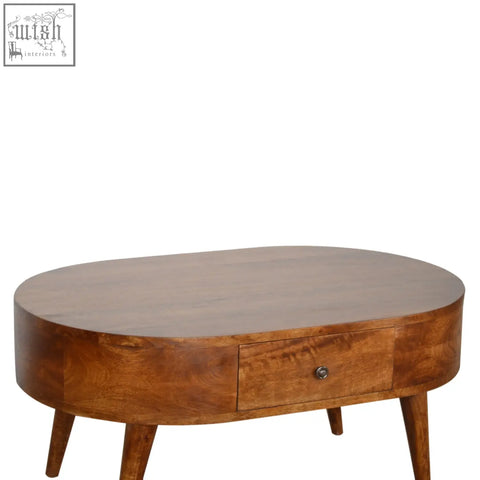 Chestnut rounded coffee table with warm toned solid mango wood, smooth oval surface, tapered legs, and single drawer knob