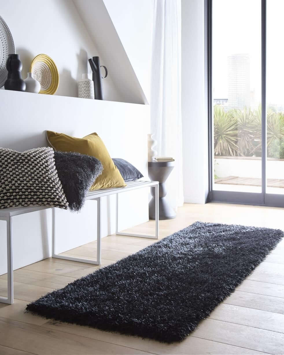 A plush chicago black shaggy rug with a soft textured surface on a light wood floor perfect for cozy spaces