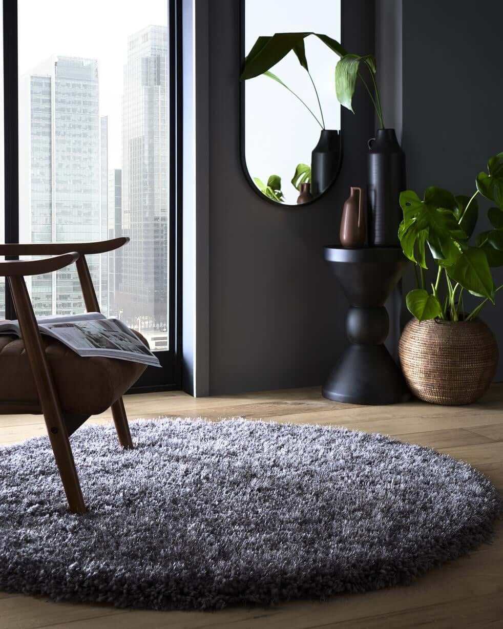 A plush round chicago grey shaggy rug with soft textured grey shaggy surface on wooden floor