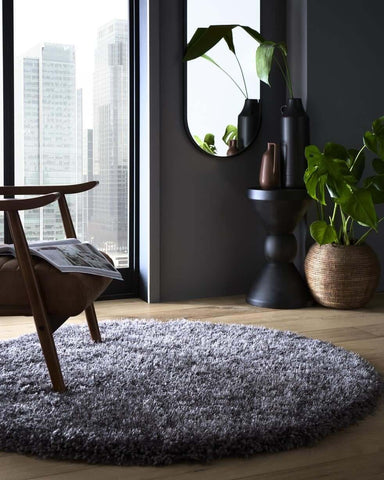 A plush round chicago grey shaggy rug with soft textured grey shaggy surface on wooden floor