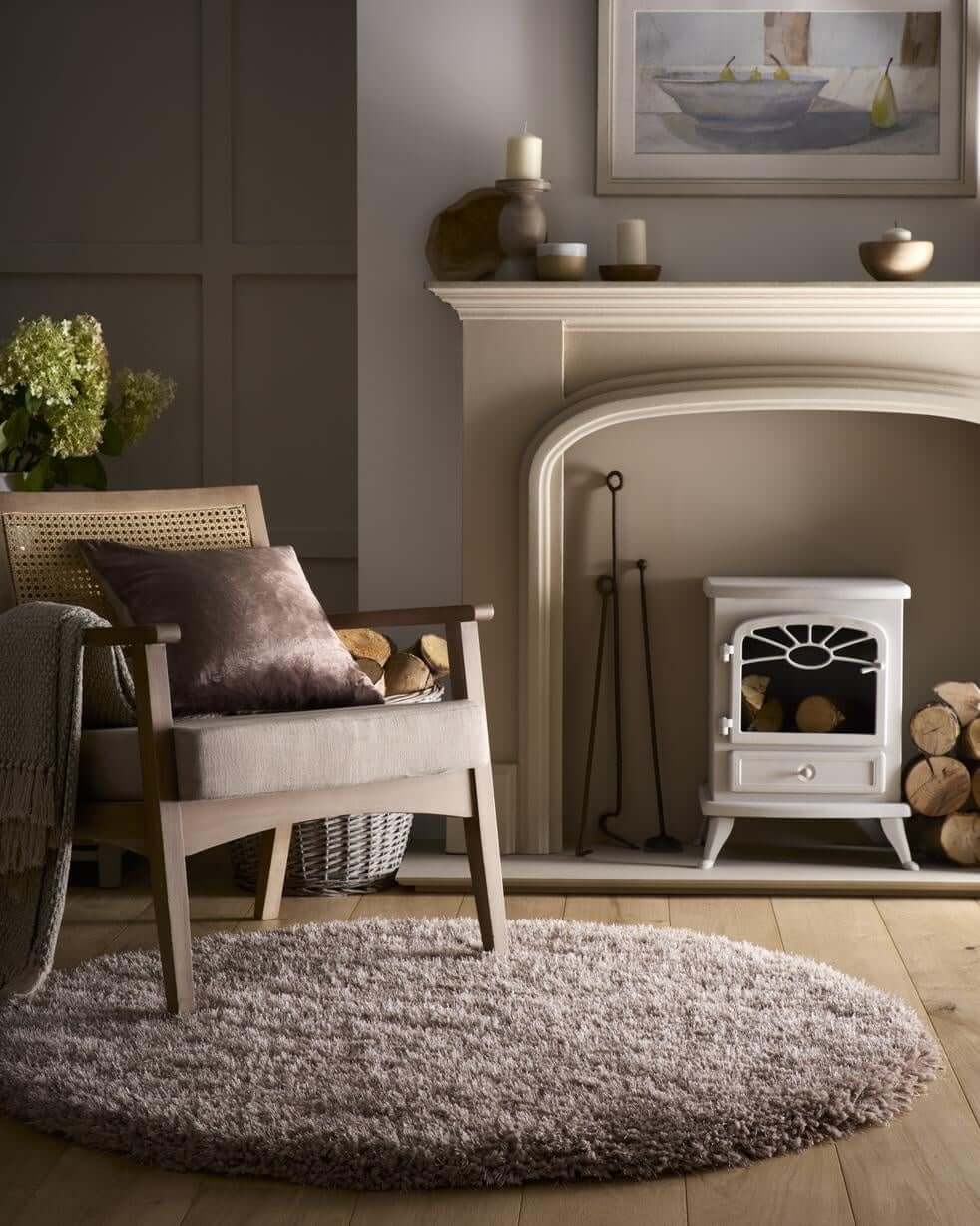 White electric fireplace with glass door and sunburst design complements the cozy chicago latte shaggy rug setting