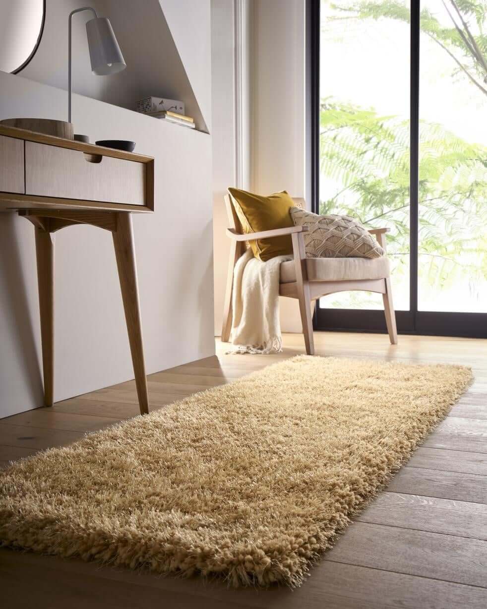 A plush chicago ochre shaggy rug with a soft textured surface in golden yellow on a wooden floor