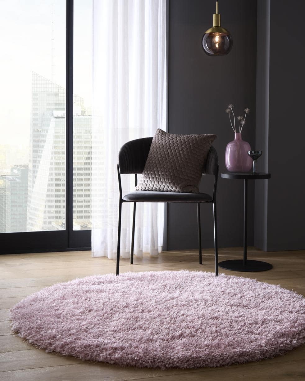 A plush round chicago pink shaggy rug with soft fluffy texture on wooden floor perfect for cozy spaces