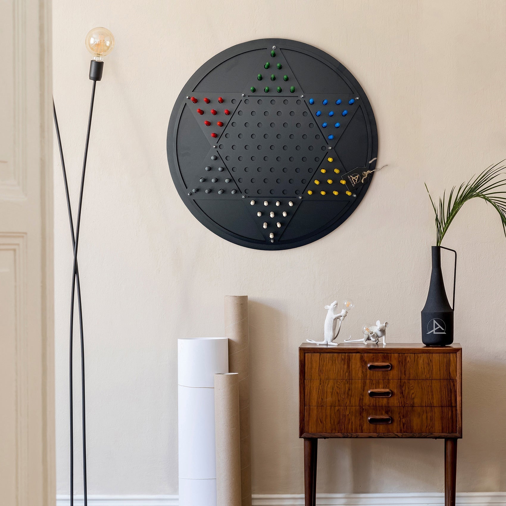 Black circular wall mounted chinese checkers board with colorful pegs arranged in a star pattern and opposite triangle design