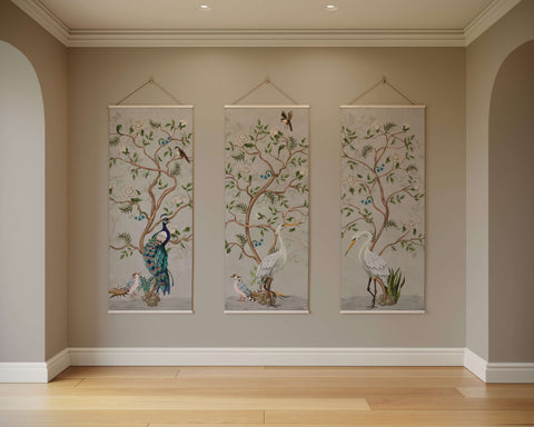 Three elegant chinoiserie bird tapestries with pastel peacocks and herons on neutral fabric hanging vertically