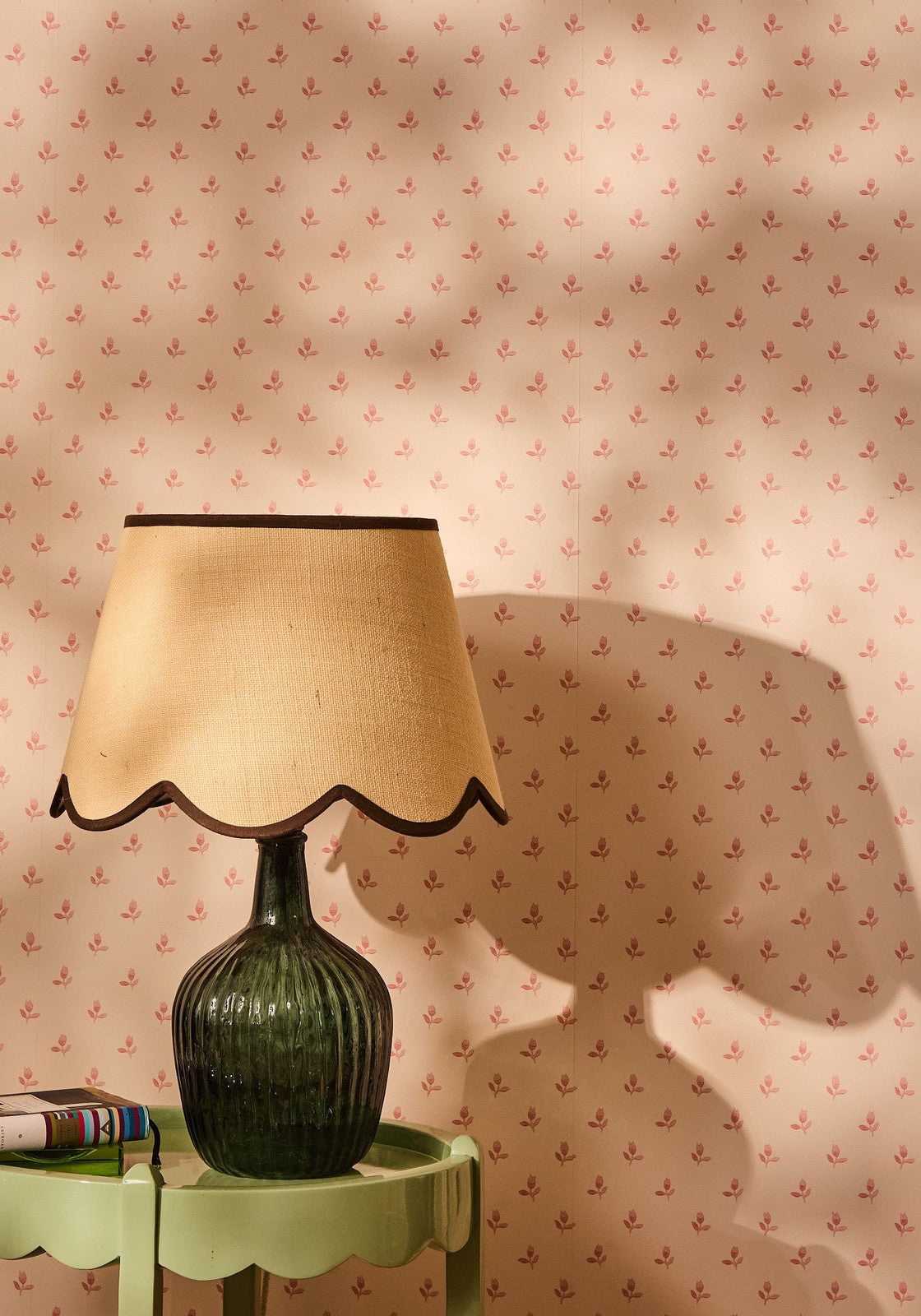 A dark green ribbed glass table lamp with a beige brown jute scallop lampshade for cozy lighting