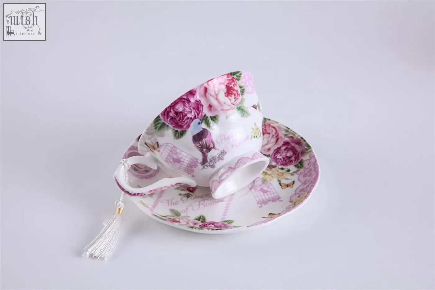 A delicate porcelain teacup and saucer with pink rose floral pattern from a bird rose milk jug and tier cake stand set