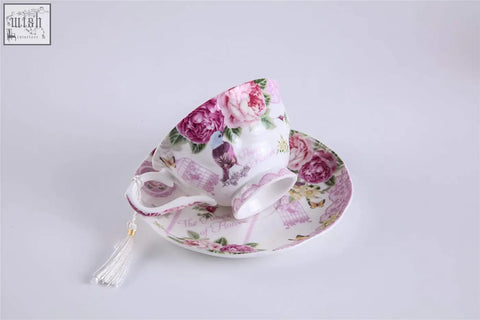 A delicate porcelain teacup and saucer with pink rose floral pattern from a bird rose milk jug and tier cake stand set