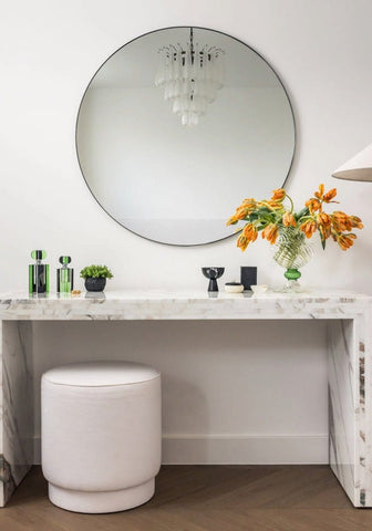 Circular mirror with a sleek black frame shown next to the small chrysler building scent bottle for stylish decor